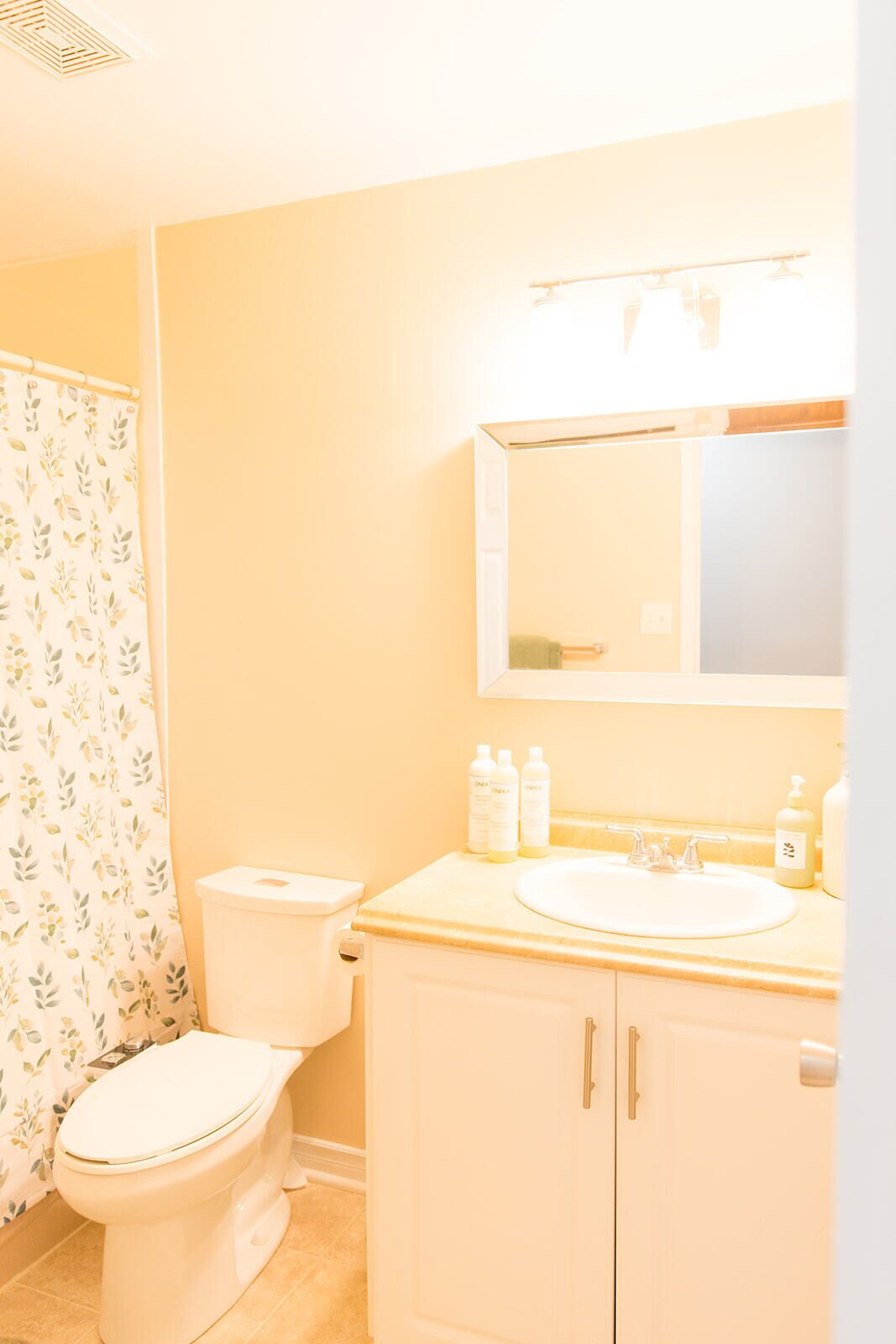 A bathroom with a toilet, a sink, and a mirror.