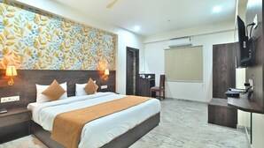 A hotel room with a bed, bedside lamps, a desk, a chair, a television, and a ceiling fan. - TrimHotel Grandview Jaipur (Jaipur)