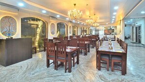 A spacious dining area with multiple tables and chairs, a reception desk, and decorative wall art. - TrimHotel Grandview Jaipur (Jaipur)