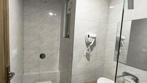A modern bathroom with a toilet, a glass-enclosed shower, a sink, and a mirror. - TrimHotel Grandview Jaipur (Jaipur)