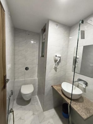 Une salle de bain moderne comprenant des toilettes, une douche à parois de verre, un lavabo et un miroir.