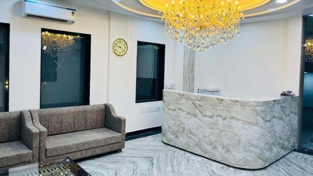 A reception area with a marble reception desk, a sofa, a chandelier, and a clock on the wall. - TrimHotel Grandview Jaipur (Jaipur)