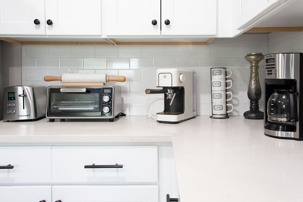 A kitchen with a toaster, a coffee maker, a rolling pin, and a coffee machine.