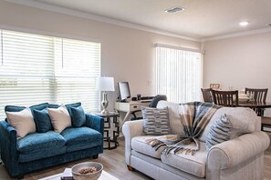 Ein Wohnzimmer mit zwei Sofas, einem Esstisch und einem Schreibtisch.
