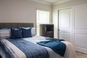Ein Schlafzimmer mit Bett, Kommode und Tür.