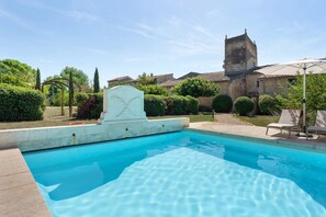 A swimming pool with a stone wall and a decorative headstone. - Olivier Apartment with Pool, Mountain View, Wi-Fi, and Air Conditioning (Cabrières-d'Avignon)