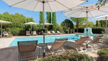 Área de piscina com espreguiçadeiras e guarda-sóis.
