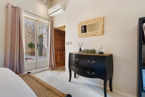 A bedroom with a bed, a dresser, a mirror, and an air conditioning unit.