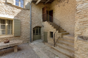 A stone building with a wooden bench, a staircase, and a door. - Olivier Apartment with Pool, Mountain View, Wi-Fi, and Air Conditioning (Cabrières-d'Avignon)