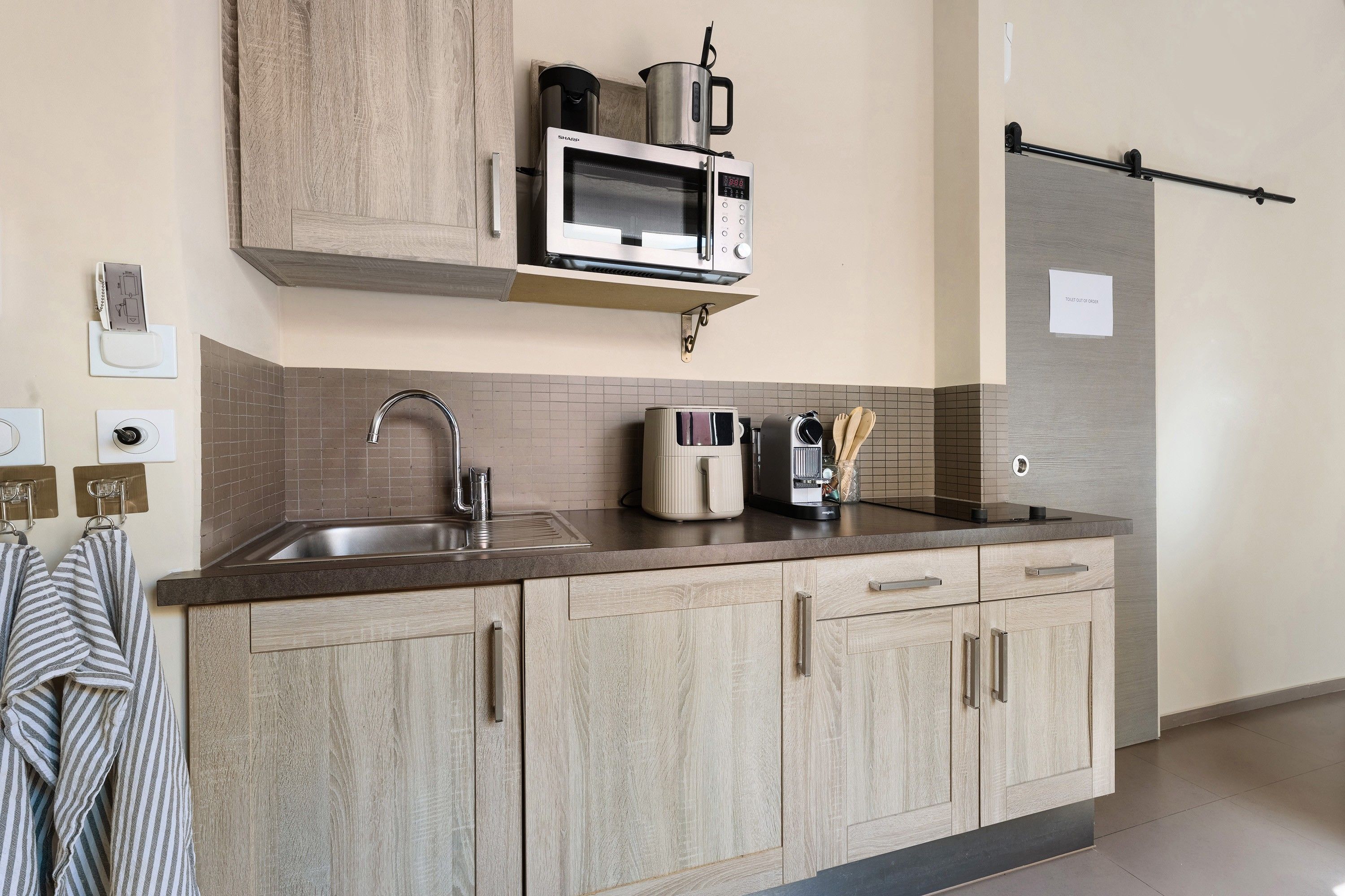 Een moderne keuken met een inbouwmagnetron, waterkoker en koffiezetapparaat.