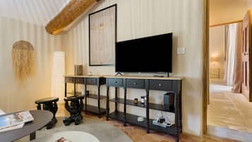 Een moderne woonkamer met een grote flatscreen televisie, een salontafel, een boekenkast en een decoratief wandobject.