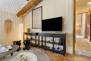 Una sala de estar moderna con un televisor de pantalla plana grande, una mesa de centro, una estantería y un elemento decorativo en la pared.