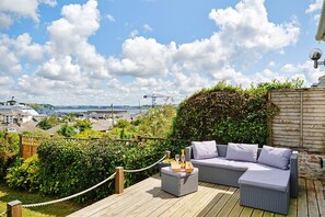 A deck with outdoor furniture and a view of a cityscape. - House With Grand Harbor Views (Falmouth)