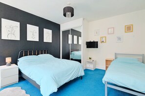 A bedroom with two beds, a large mirror, artwork on the walls, and a TV on the wall. - House With Grand Harbor Views (Falmouth)