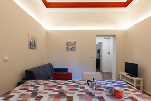 Ein Zimmer mit einem Bett, einem Fernseher und einem Couchtisch. An der Wand hängen zwei Bilder.