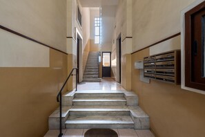 Eine Treppe führt zu einer oberen Etage, mit Handlauf, einer Tür oben und einem Fenster, das natürliches Licht hereinlässt.