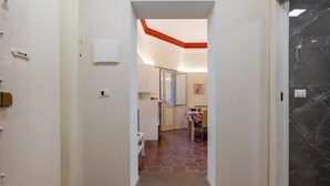 En hall som leder till ett kök med ett kaklat golv och en röd accentvägg.