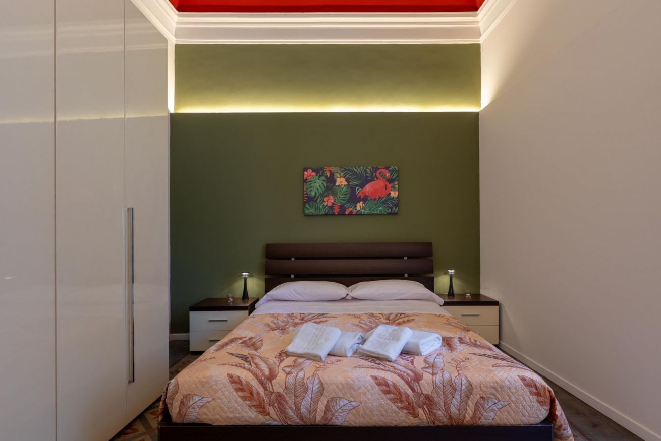 Une chambre à coucher avec un lit, des tables de chevet, une armoire et un tableau au mur.