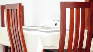 Un comedor con sillas de madera y una mesa cubierta con mantel blanco.