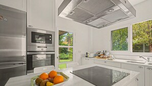 A modern kitchen with a built-in oven, microwave, and a large island with a glass top. - Stunning private villa in Sotogrande (Zone C) with garden, private pool, and Wi-Fi (San Roque)
