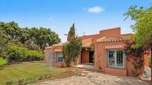 A building with a stone patio, a garden, and a clear blue sky. - Stunning private villa in Sotogrande (Zone C) with garden, private pool, and Wi-Fi (San Roque)