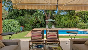 An outdoor seating area with a pool, surrounded by lush greenery. - Stunning private villa in Sotogrande (Zone C) with garden, private pool, and Wi-Fi (San Roque)