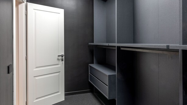 A room with a white door, a dark wall, and a built-in shelf unit.