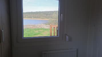 Una habitación con ventana que da a un lago y una zona cubierta de césped.