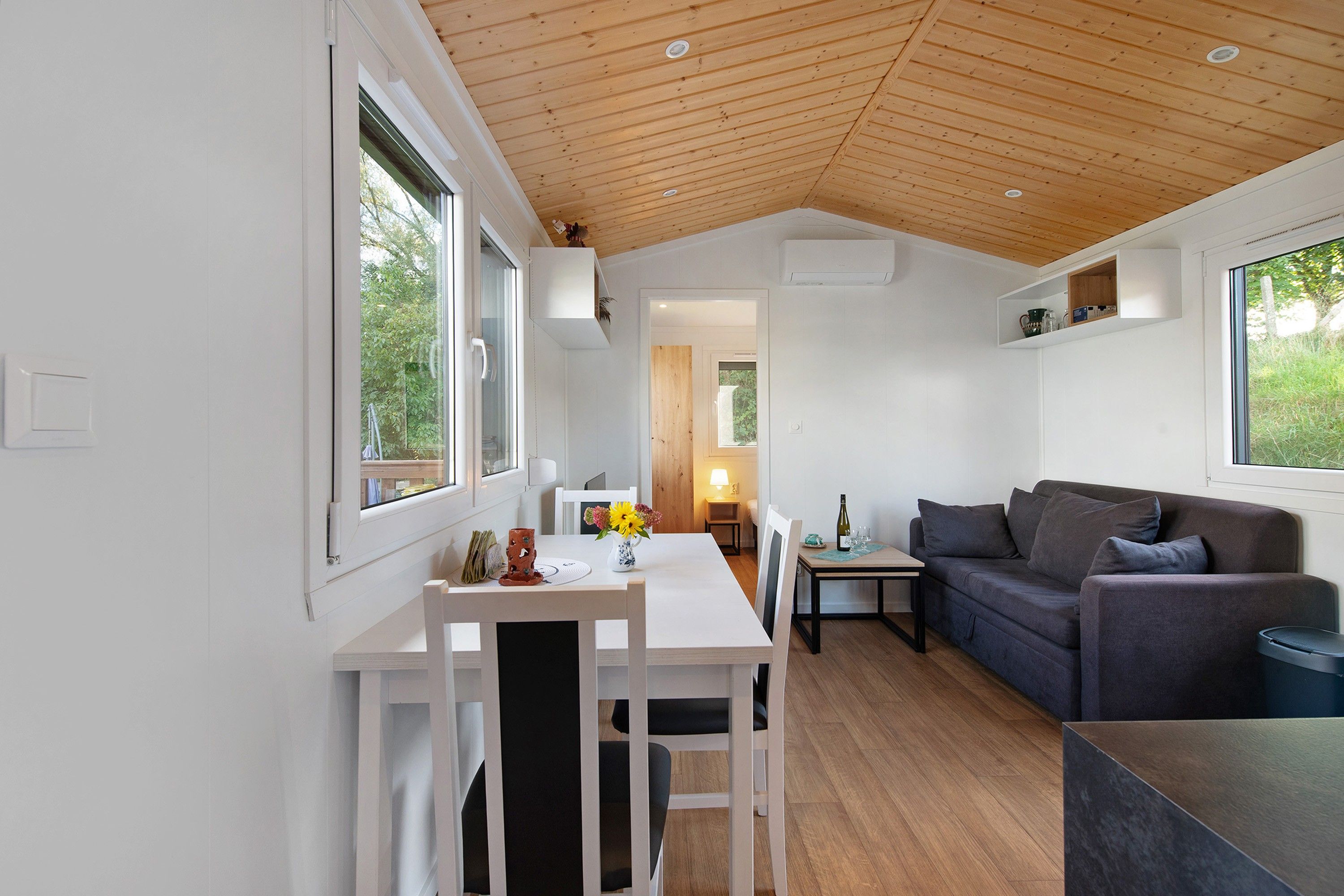 Ein modernes Interieur mit Essbereich, einer Couch und einer Holzzieldecke.