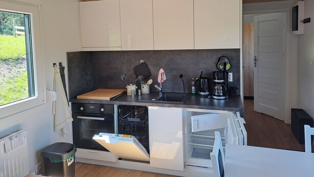 A compact kitchen with a built-in oven, a dishwasher, and a coffee maker.