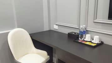 A modern room with a dark wooden desk, a white chair, and a trash bin.