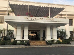 La entrada del hotel White Palace Lansdon, con un acceso cubierto y escalones que conducen a la puerta.