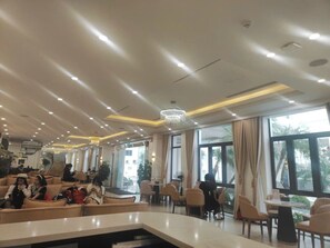 Vestíbulo de hotel con zonas de estar, una escalera y grandes ventanales.