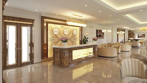 A reception area with a marble reception desk, two clocks, and a reception sign. - White Palace Quynh Coi (Quynh Phu)