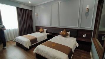 Habitación de hotel con dos camas, un ventanal con cortinas y suelo de madera.