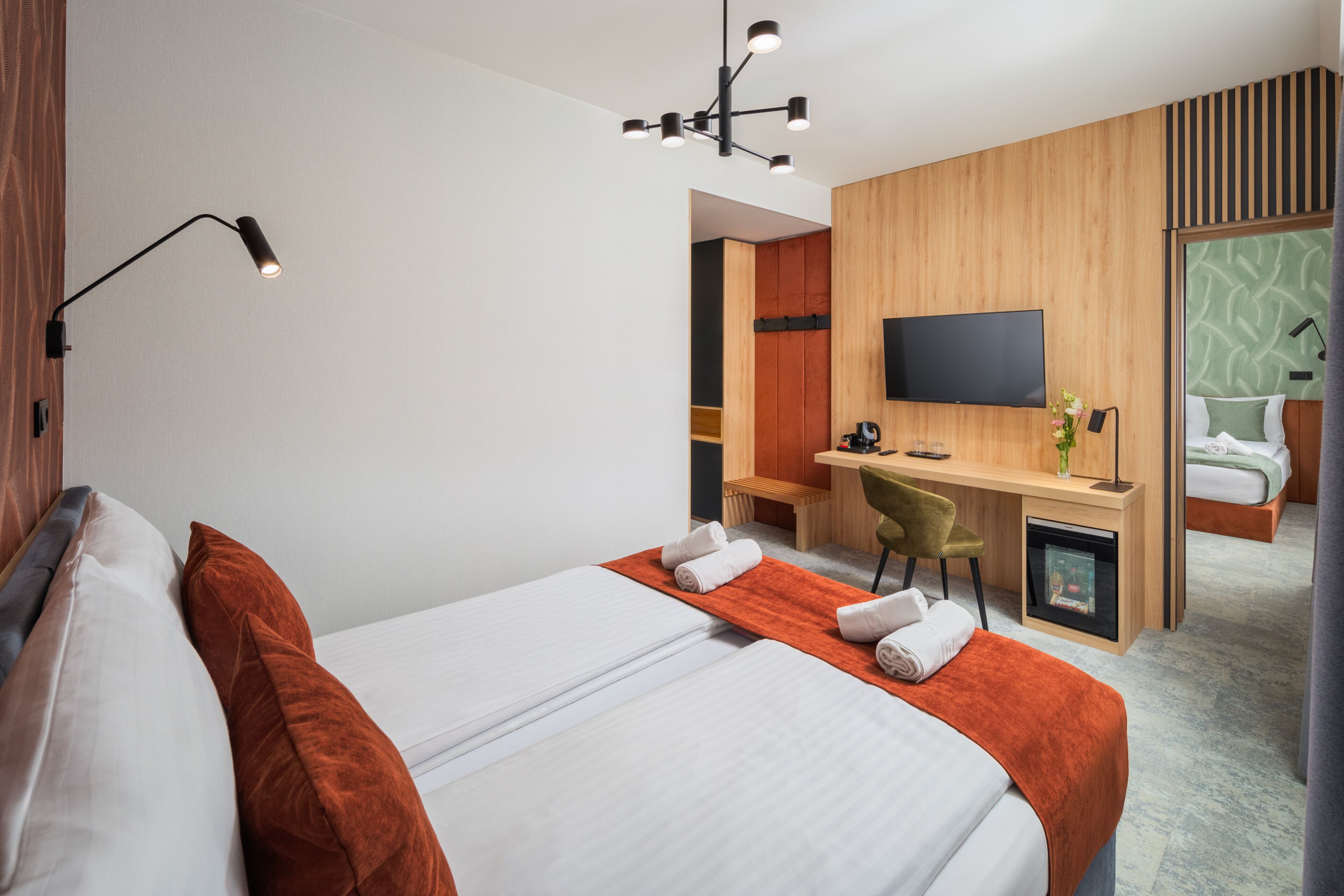 Een hotelkamer met een bed, een bureau, een stoel, een televisie en een badkamer zichtbaar door een geopende deur.