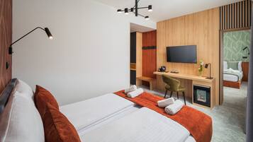 Een hotelkamer met een bed, een bureau, een stoel, een televisie en een badkamer zichtbaar door een geopende deur.