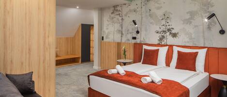 Habitación de hotel moderna con una cama grande, una mesita, un sofá y un papel tapiz con motivos naturales.