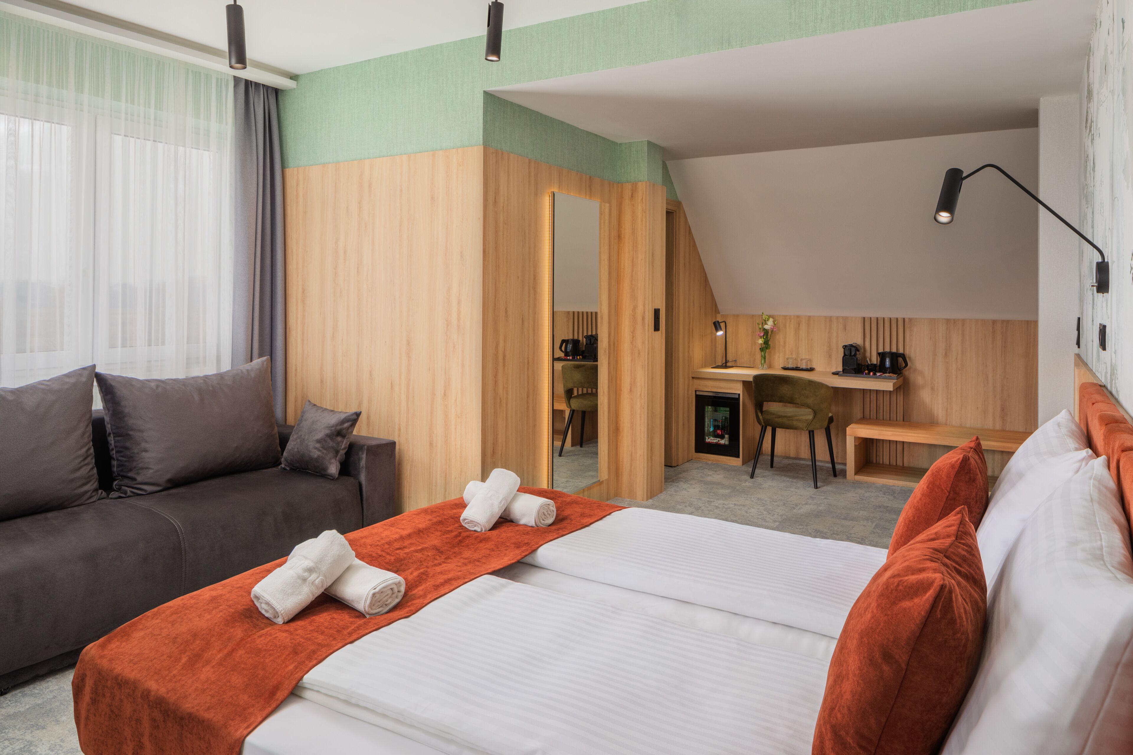 Una habitación de hotel con cama, escritorio, sofá y espejo.