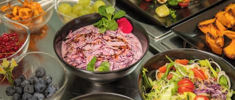 A buffet with various food options including salads, fruits, and vegetables.