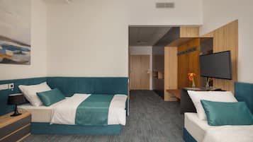 Habitación de hotel con dos camas, un televisor de pantalla plana, un escritorio con lámpara y un cuadro en la pared.