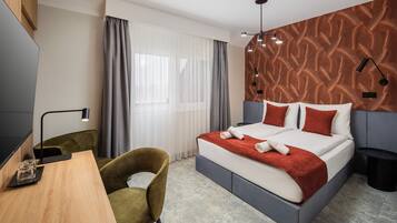 Une chambre d’hôtel moderne équipée d’un lit, d’un bureau, d’une chaise et d’un téléviseur.