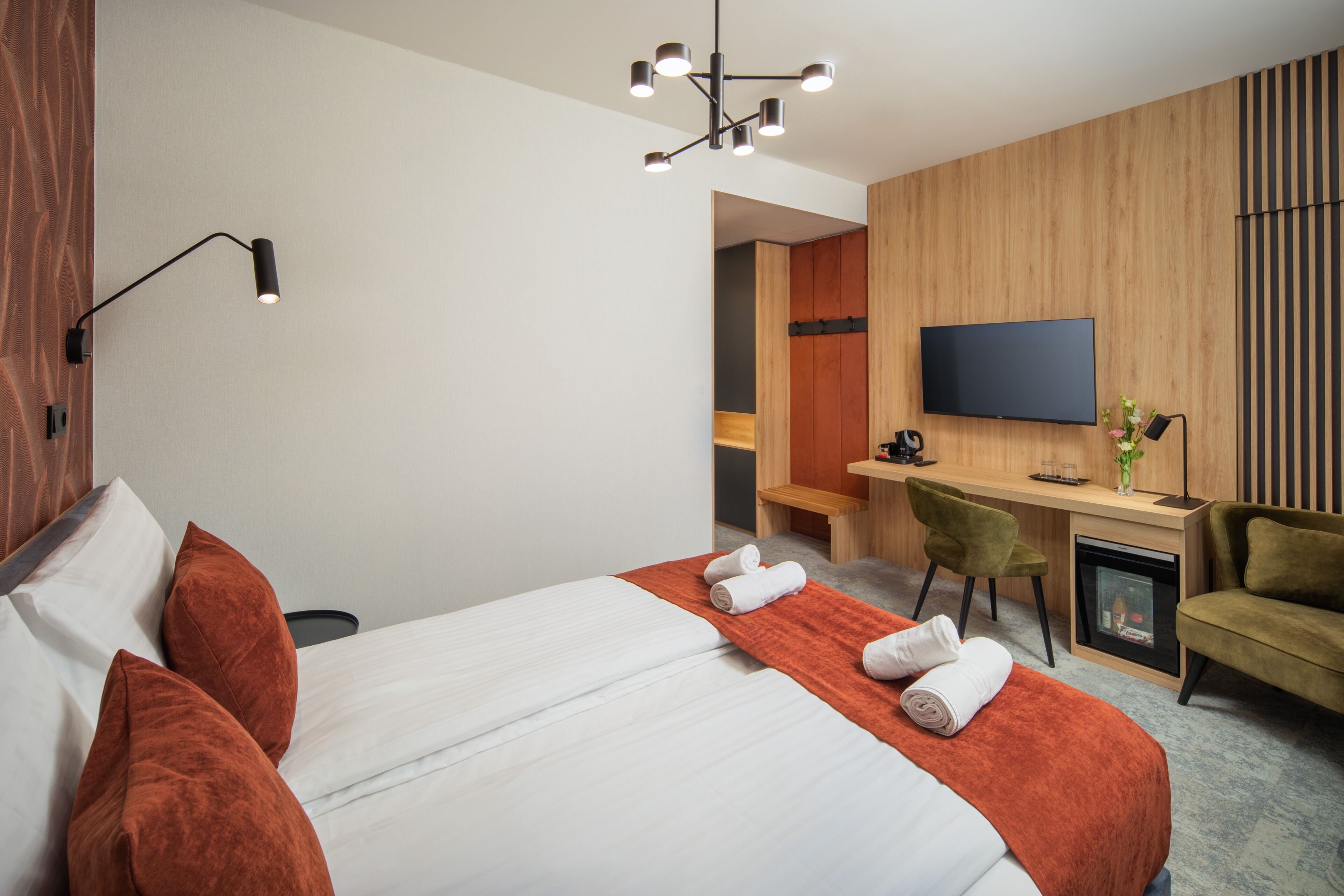Een hotelkamer met een bed, een bureau, een televisie en een zithoek.