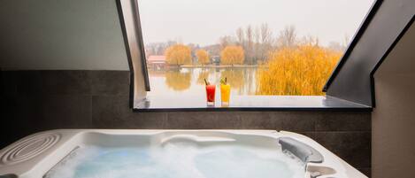 A hot tub with a view of a lake and autumn trees.