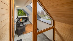 A room with a sloped ceiling, a hot tub, and a view of a park. - Sziget Hotel (Nyíregyháza)