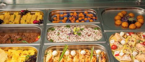 Un buffet proposant une variété de plats, notamment du riz, de la viande et des légumes.