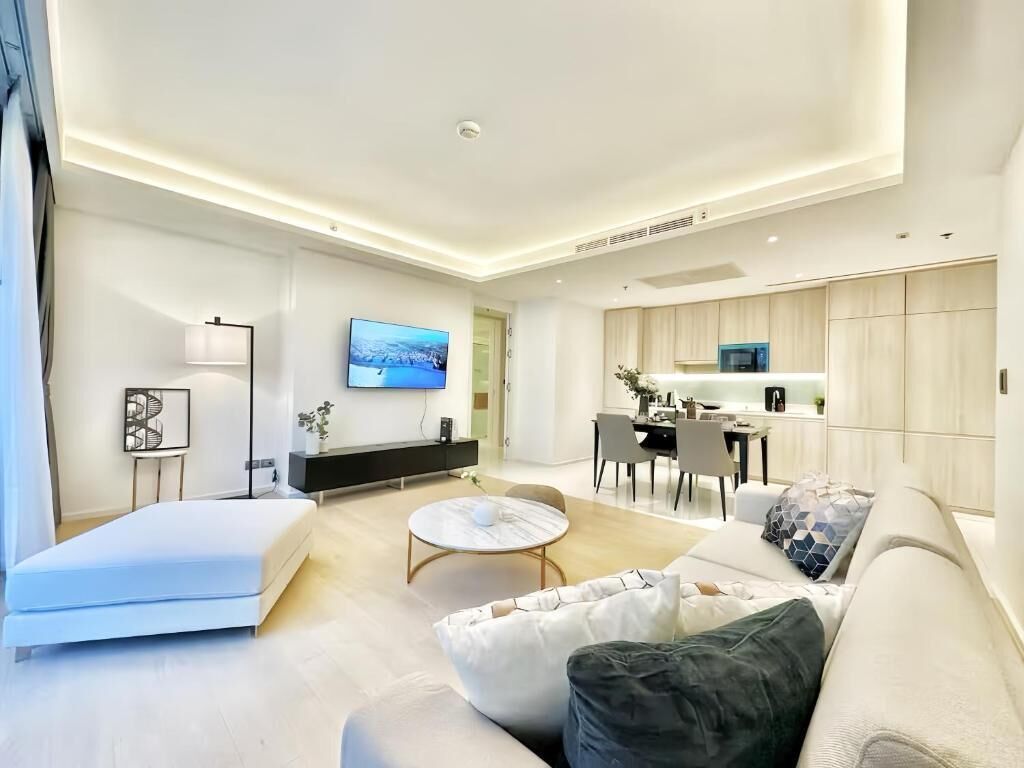 A modern living room with a sofa, a coffee table, and a flat-screen TV mounted on the wall.