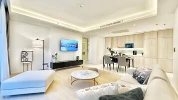 A modern living room with a sofa, a coffee table, and a flat-screen TV mounted on the wall.