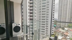 Een hoog gebouw met uitzicht op andere gebouwen en een balkon met een Samsung wasmachine.