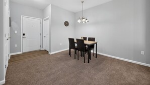 Quarto com uma mesa de jantar, cadeiras, um relógio e uma porta.
